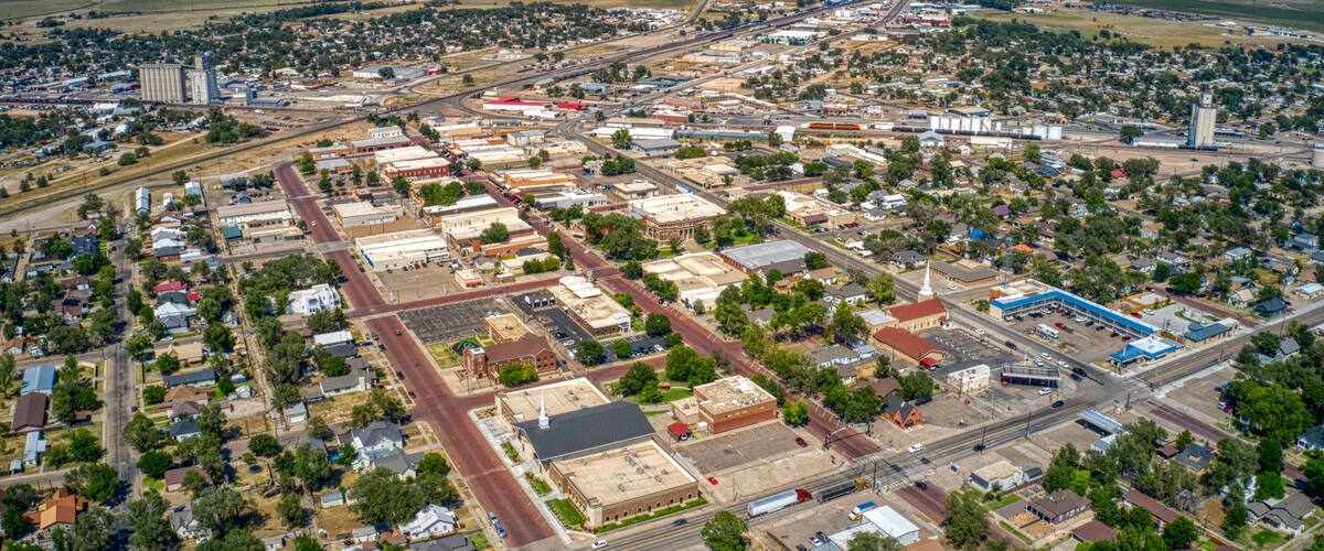 An aerial view of a town with a mix of residential and commercial buildings, a prominent church, and a large industrial area.