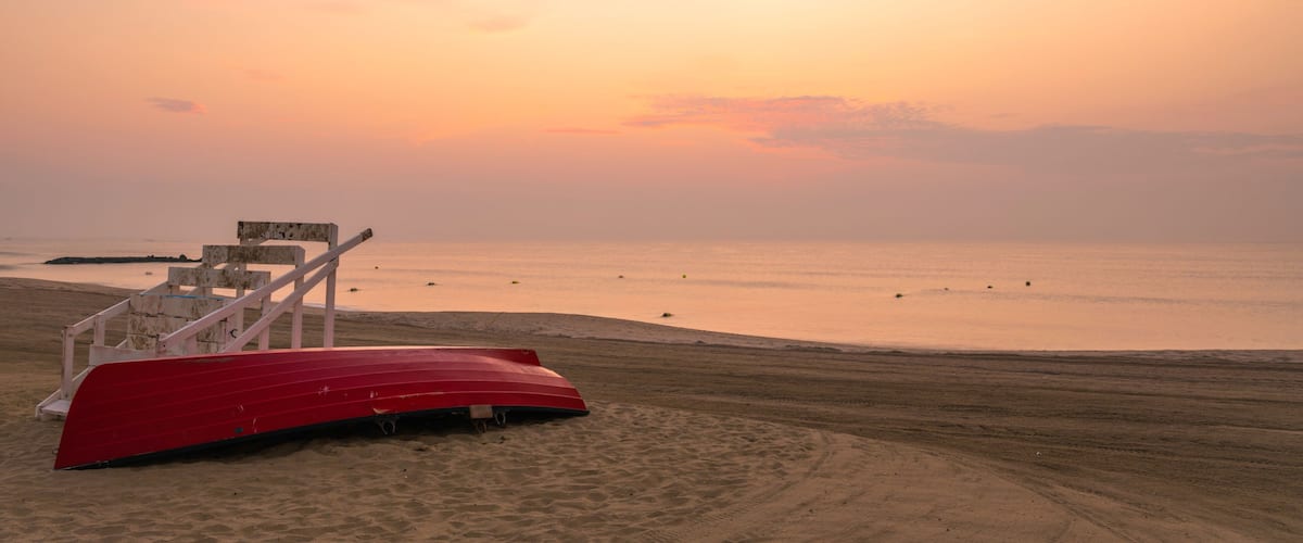 Beautiful sunrise over Avon By The Sea beach in New Jersey, featuring wooden boat and sand on the foreground