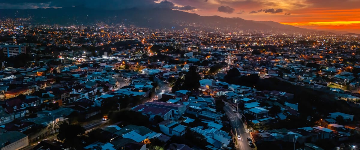 A cityscape at dusk with a mountain in the background.