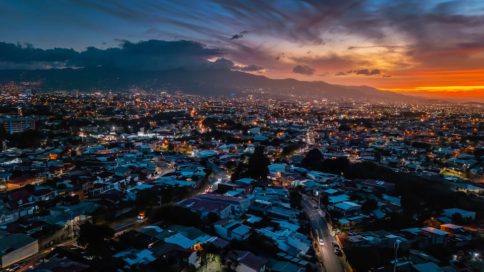 A cityscape at dusk with a mountain in the background.