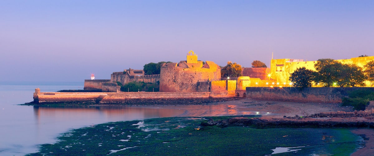 A historic fort with a lighthouse, surrounded by water and greenery.