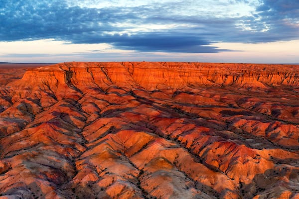 A vast, rugged terrain with layered rock formations and a dramatic sky.