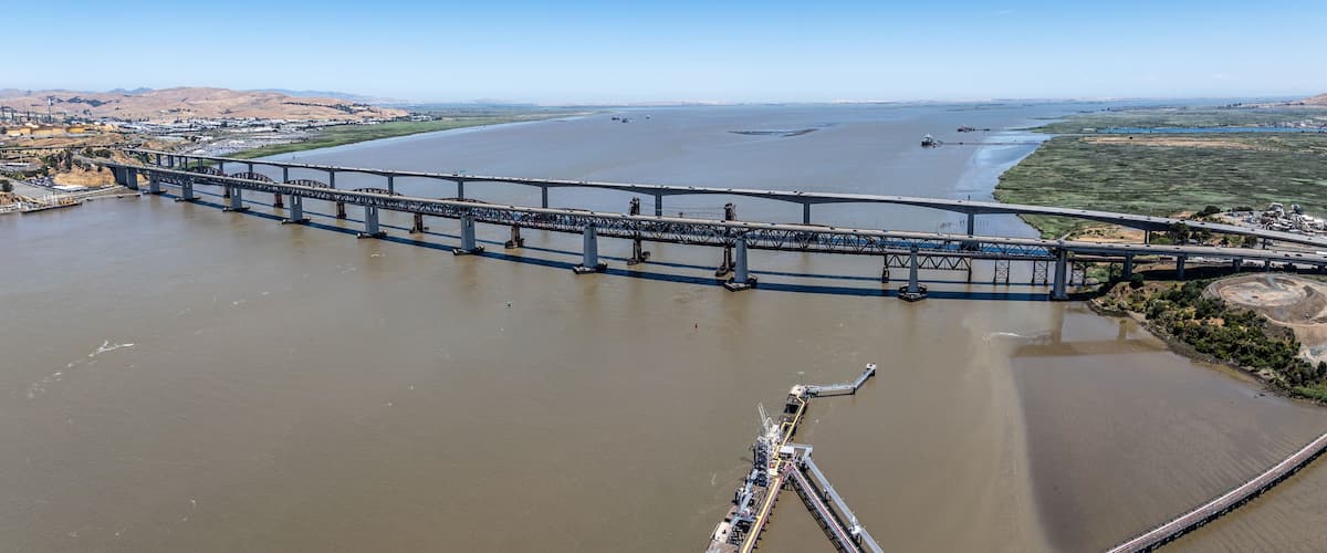 Un puente grande que cruza un río ancho, con estructuras industriales cerca.