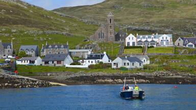 A coastal village with a church, houses, and a boat on the water.