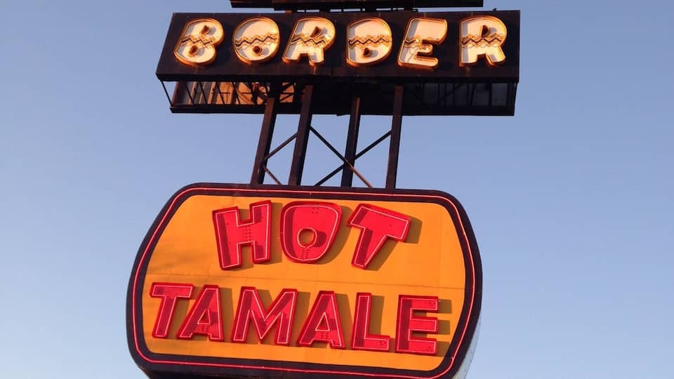 A sign for 'South of the Border Hot Tamale' with 'Open 24 Hours' written below.
