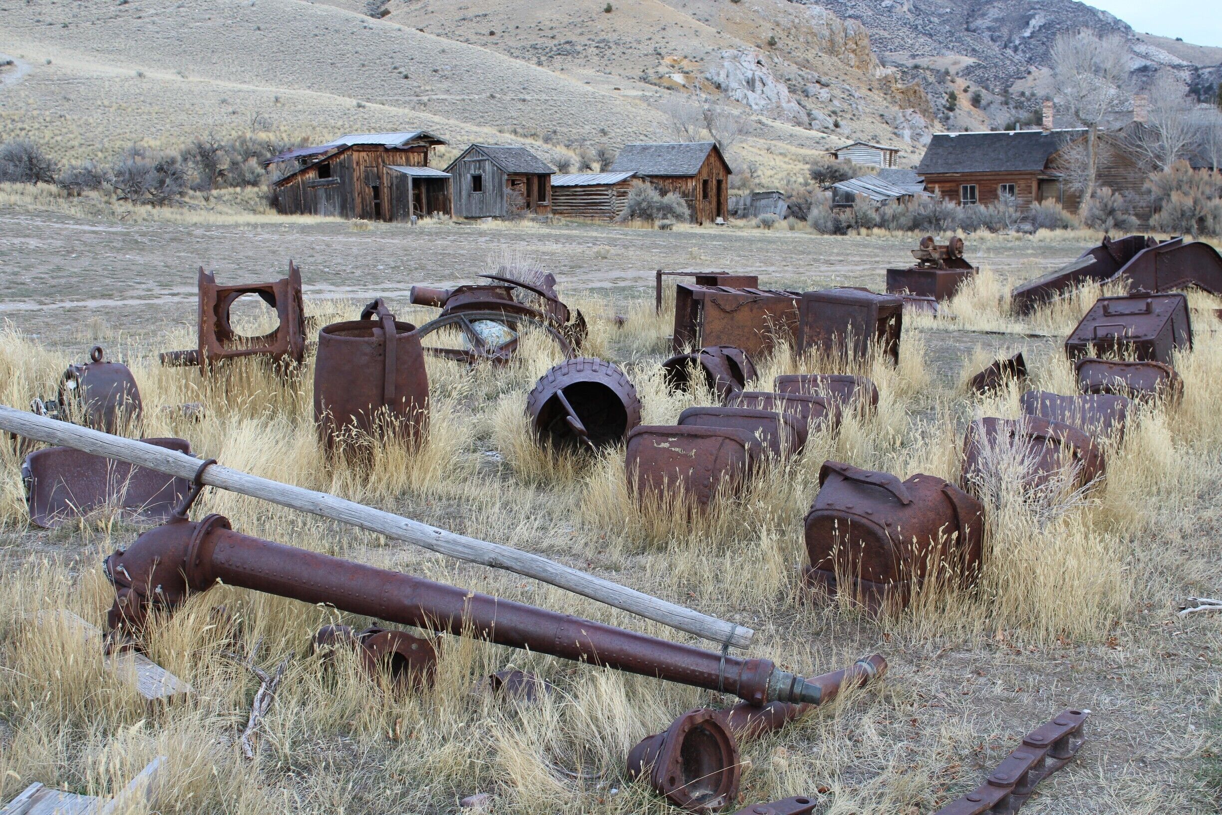 A rural landscape with rusted metal objects and old wooden buildings.