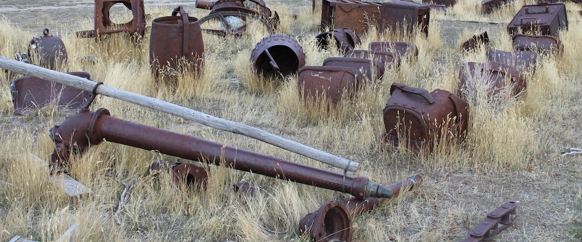 A rural landscape with rusted metal objects and old wooden buildings.