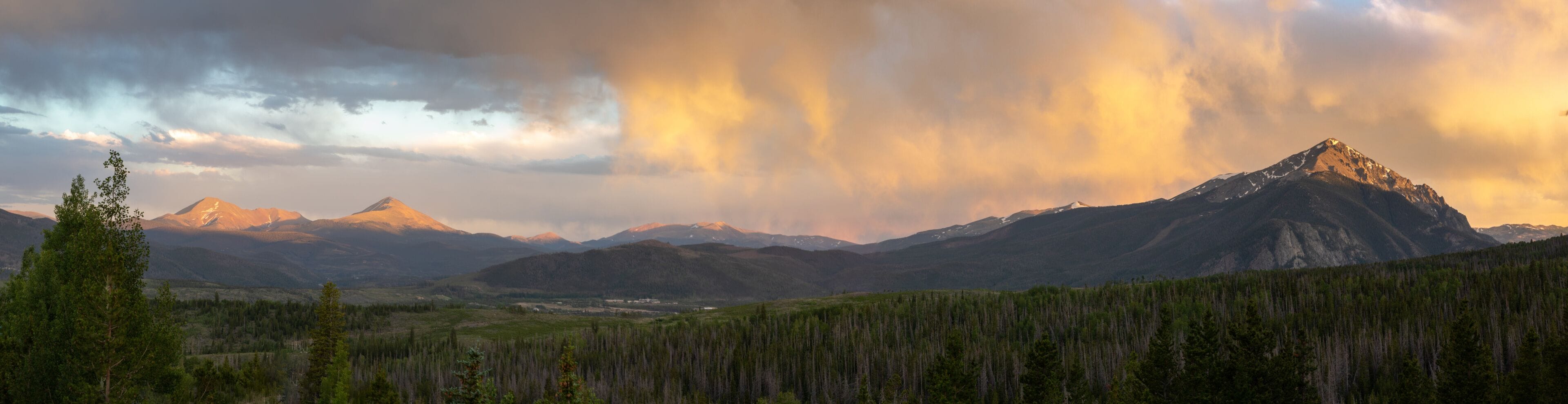 A mountain range with a prominent peak, dense forest, and a valley.