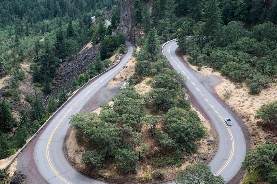 A winding mountain road surrounded by dense forests and rocky cliffs.