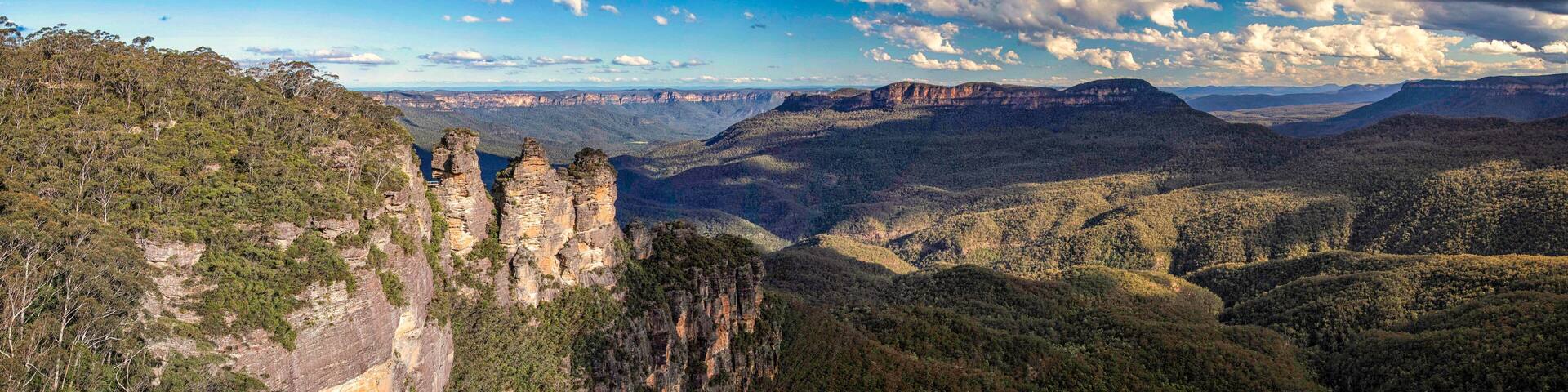 A canyon landscape with prominent rock formations and dense forested hills.