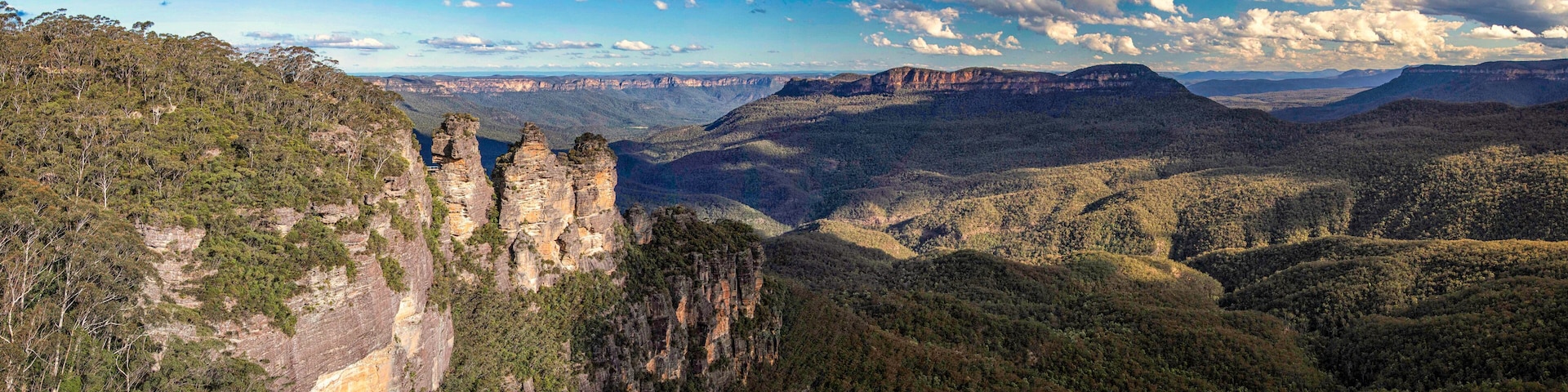 A canyon landscape with prominent rock formations and dense forested hills.