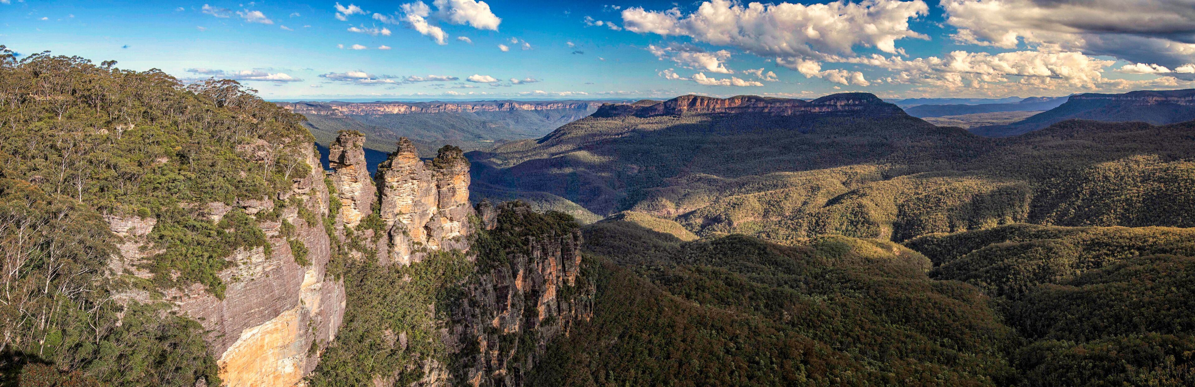 A canyon landscape with prominent rock formations and dense forested hills.
