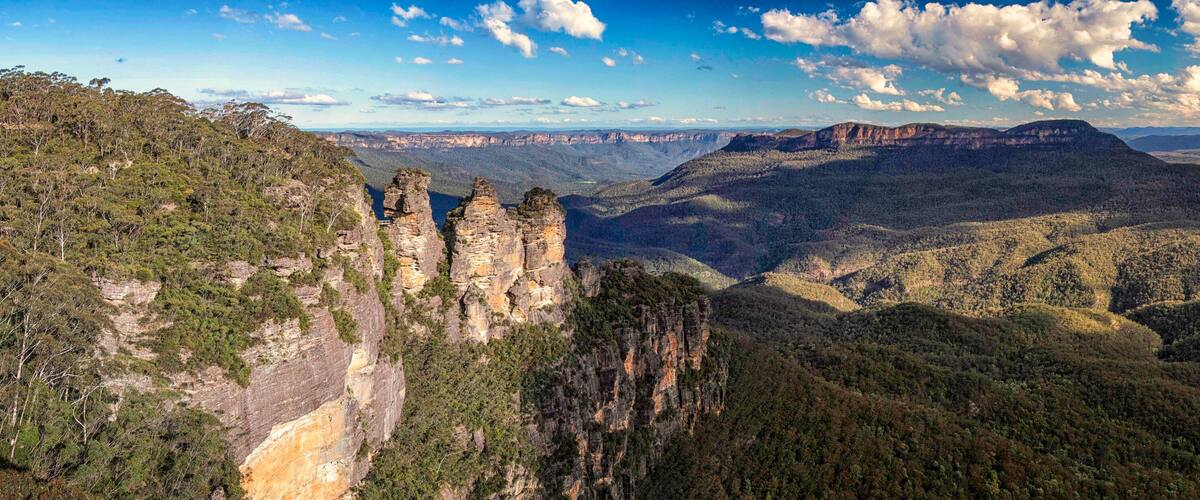 A canyon landscape with prominent rock formations and dense forested hills.
