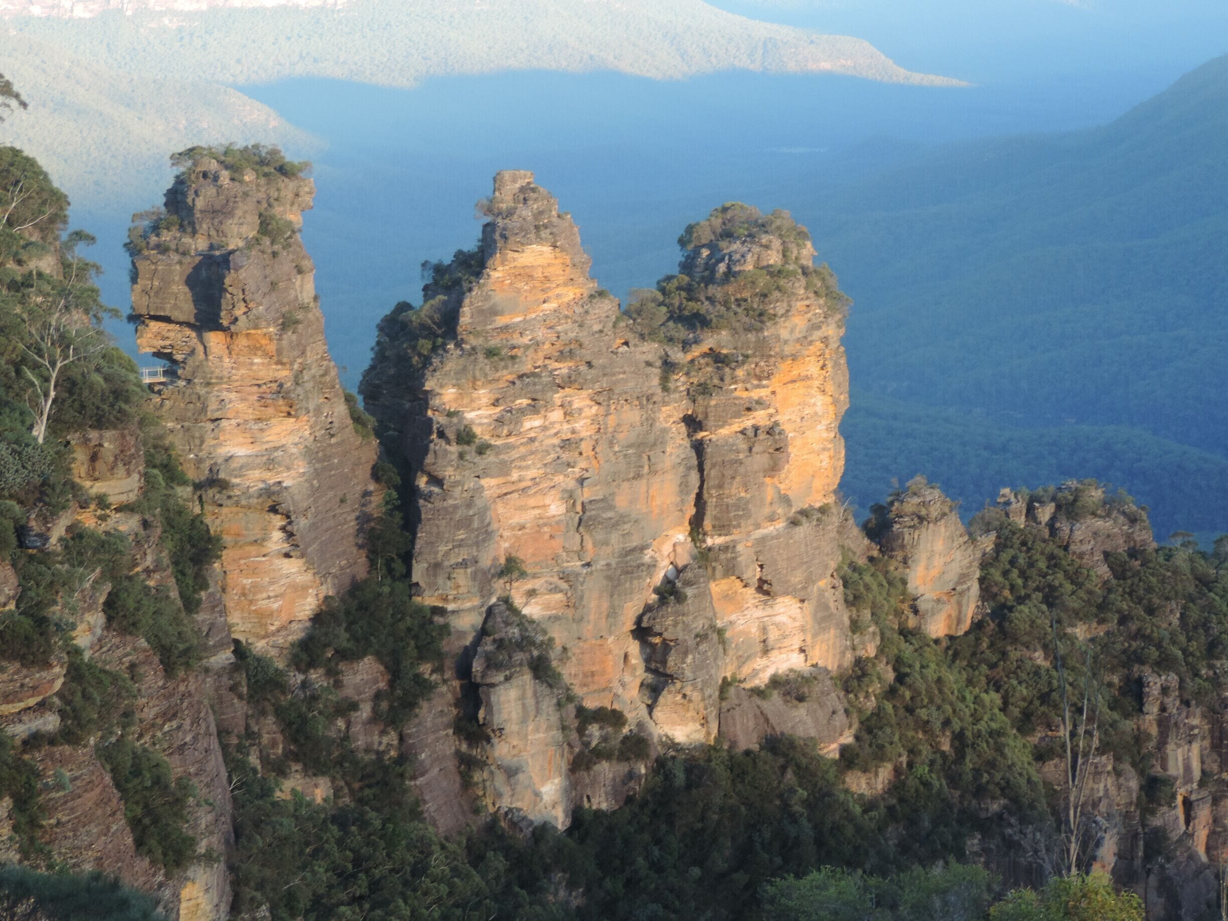 A landscape of towering rock formations with a river and distant mountains.