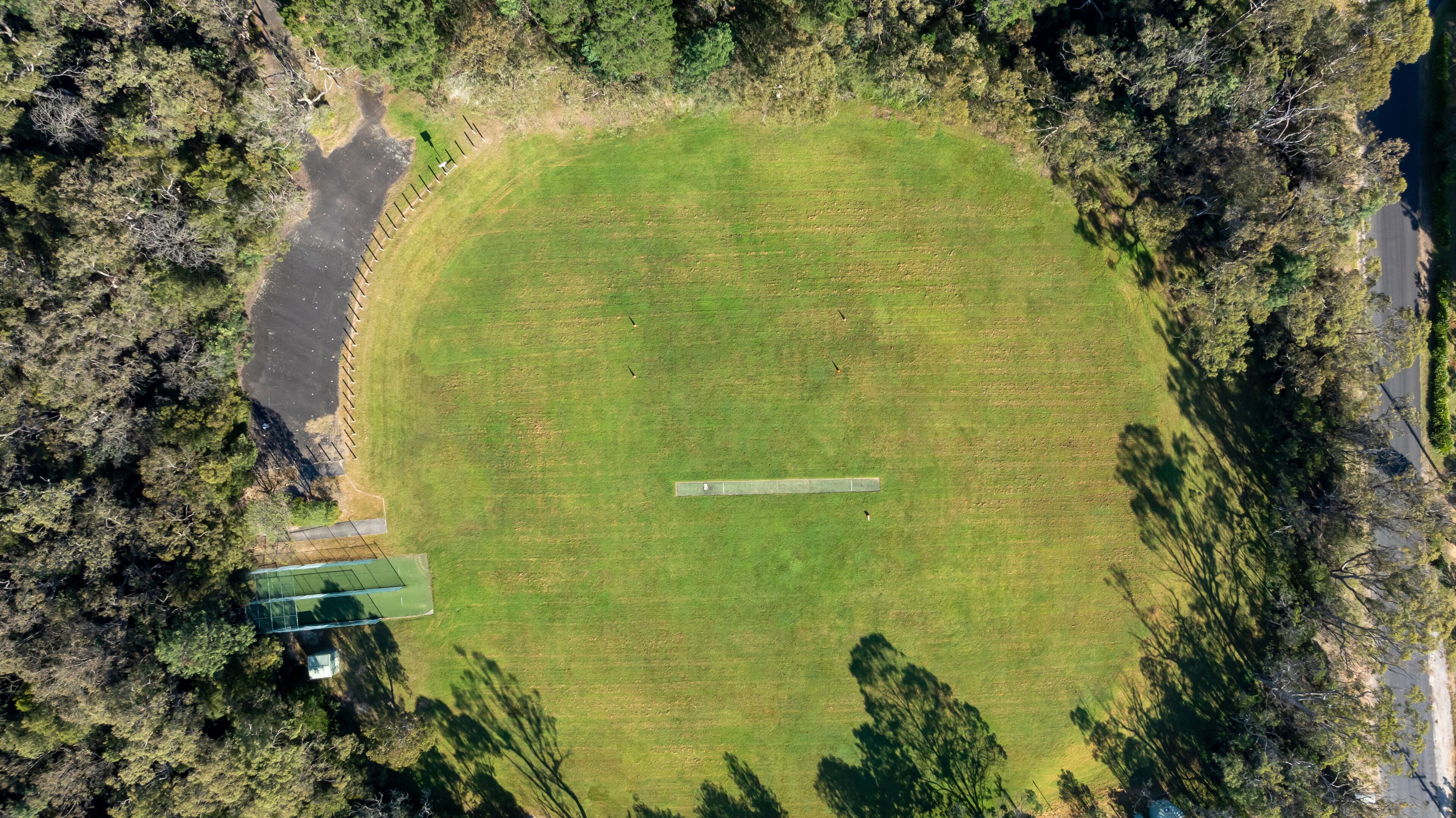 Vista aérea de un campo verde circular con un sendero pavimentado y un pequeño edificio.