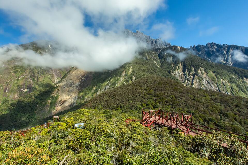 A mountainous landscape with a red bridge and lush greenery.
