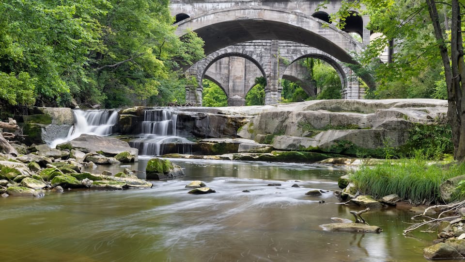 A waterfall, a river, and a stone bridge with arches.