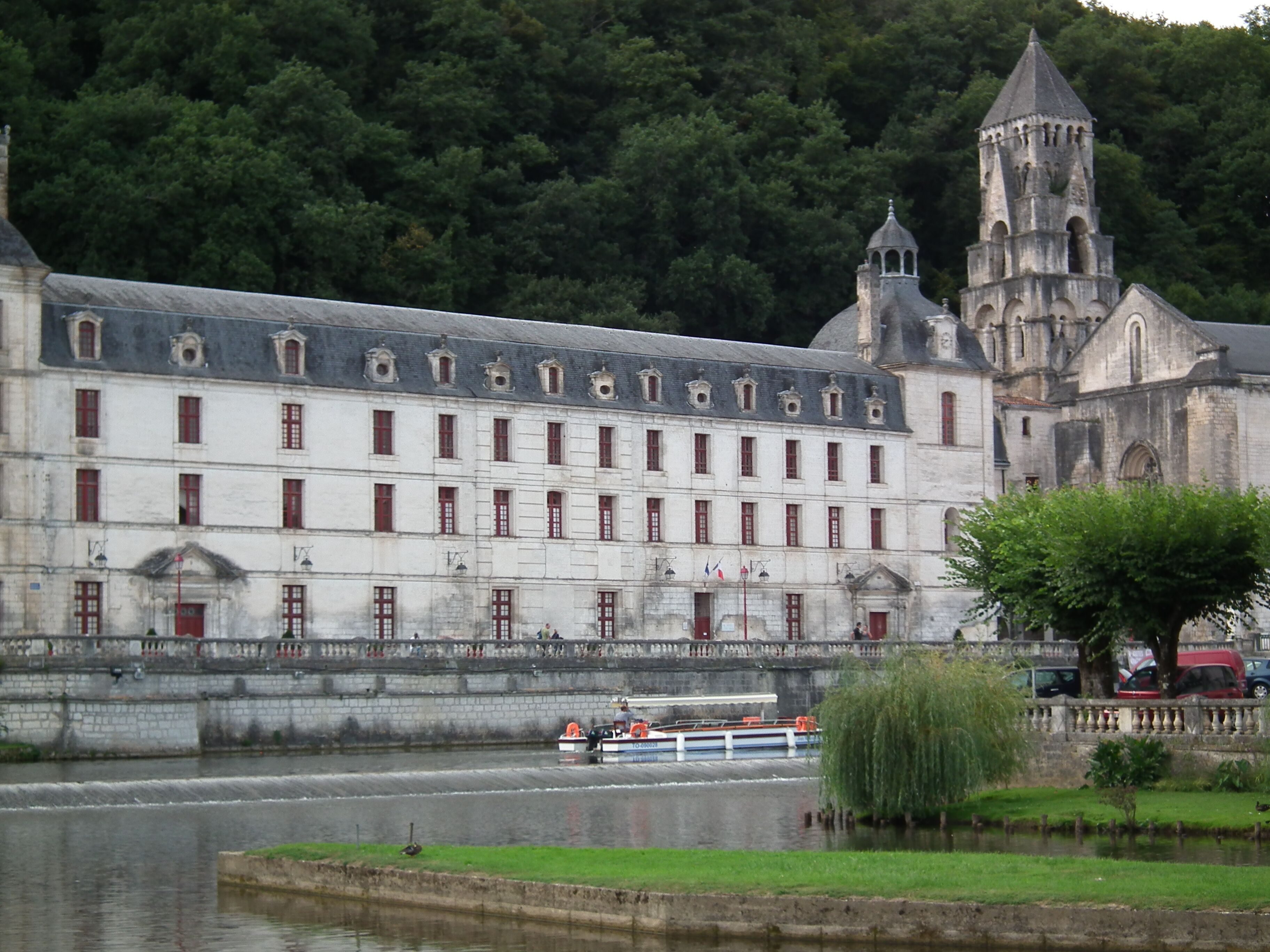 A historic building with a tower and a river in front.