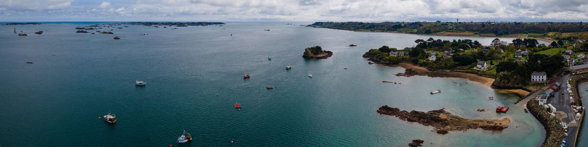A coastal town with boats on the water, rocky outcrops, and houses along the shore.