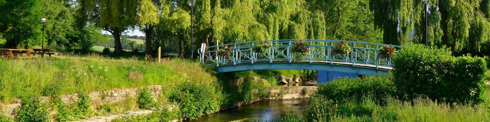 Panoramique La Loisance traversée par un pont fleuri, coule dans un parc de verdure à Antrain (35560 Val-Couesnon), département d'Île-et-Vilaine en région Bretagne, France