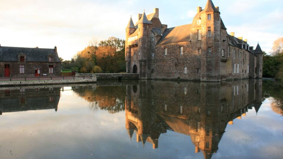 A historic castle with a moat, reflecting its architecture.