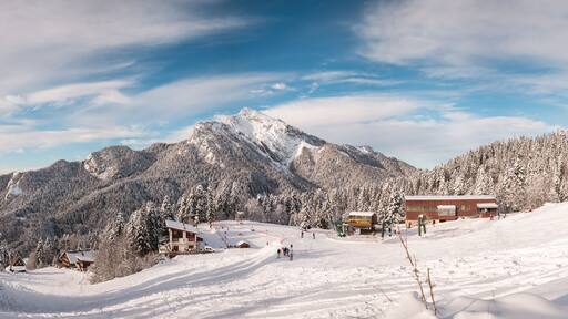 Eine verschneite Berglandschaft mit Skihütten und blauem Himmel.