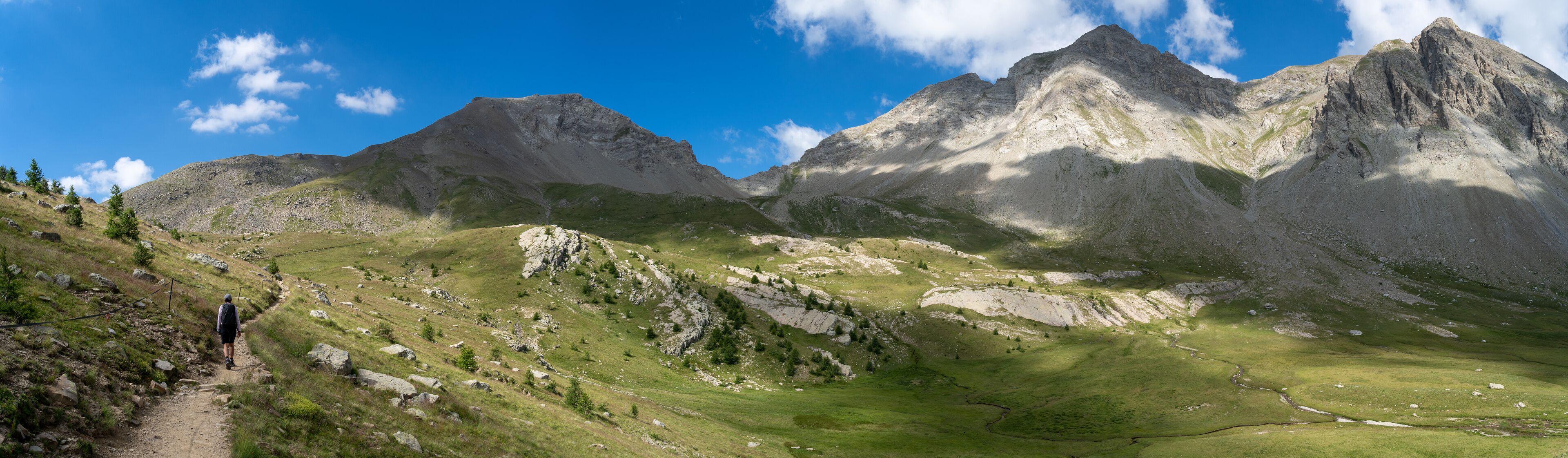 A mountainous landscape with a clear sky, a winding path, and rocky terrain.