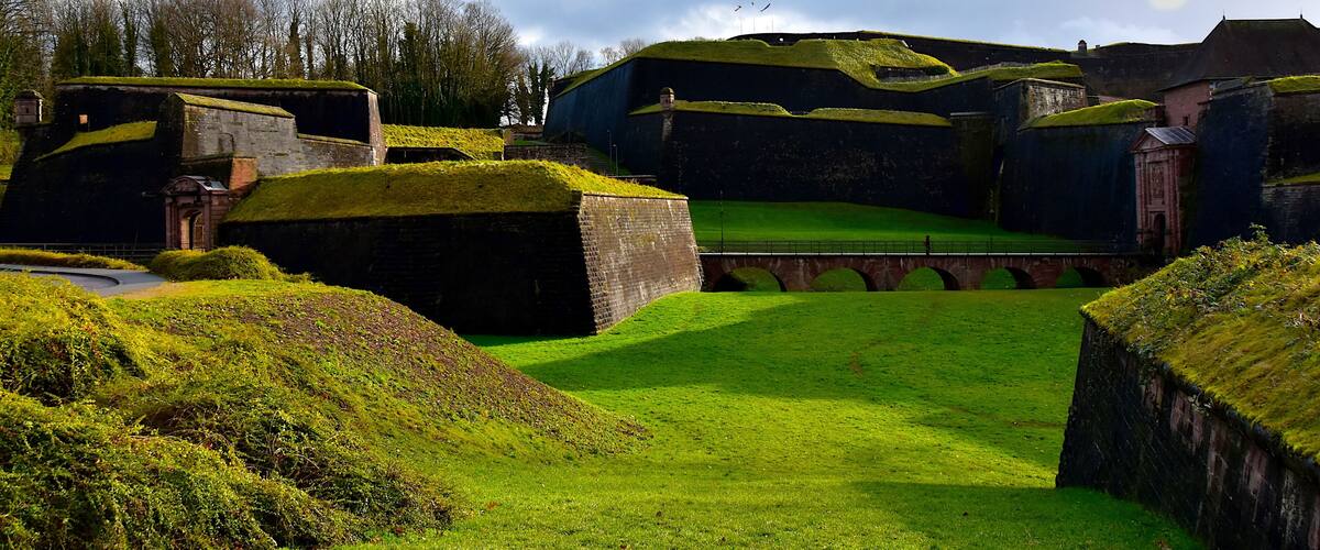 A historic fort with green turrets and a grassy courtyard.