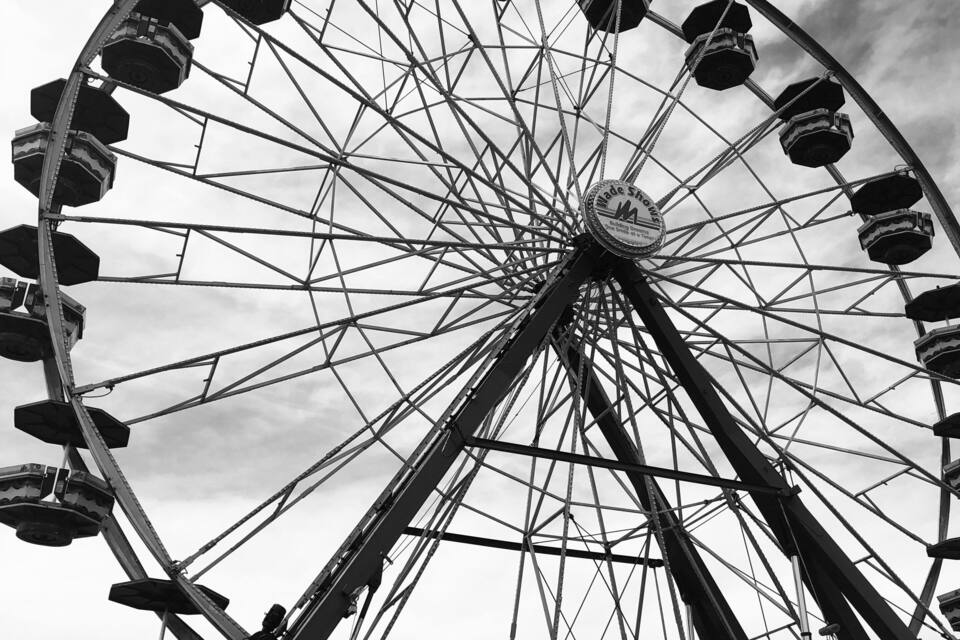 A large Ferris wheel at a fair with people around it.