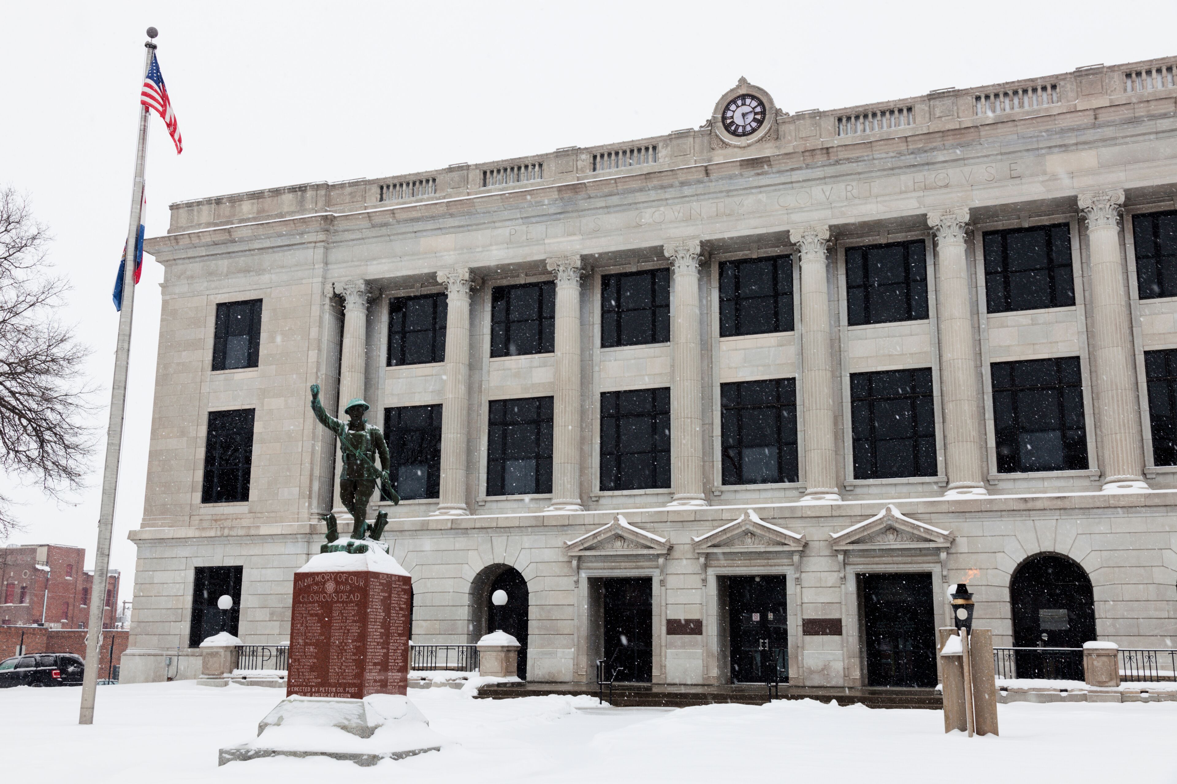 A large, classical building with columns and a statue in front.