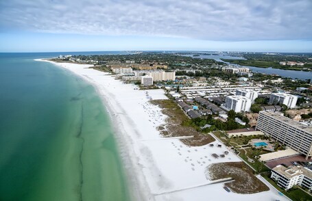 A coastal city with a long sandy beach, a marina, and several high-rise buildings.