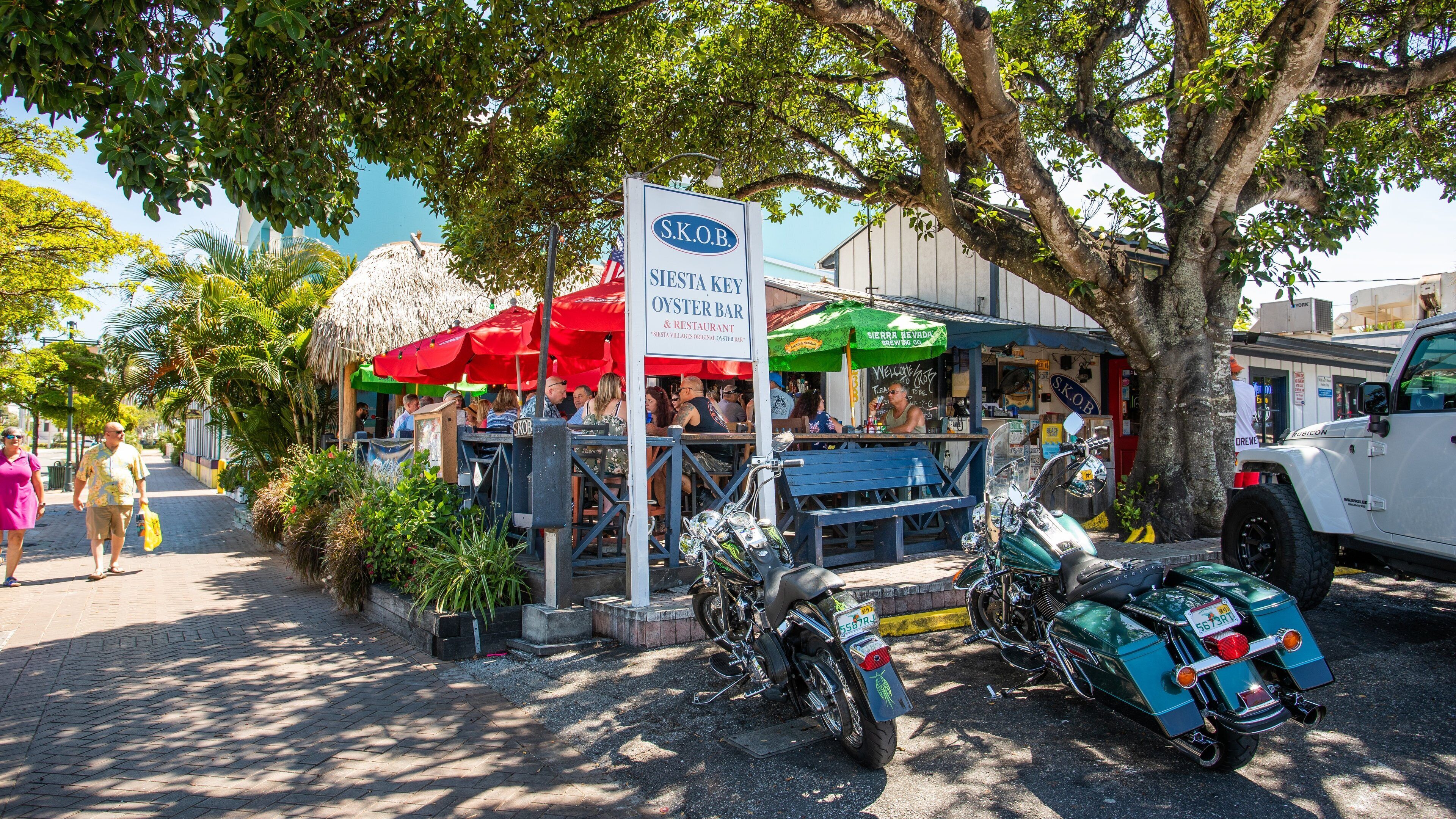 An outdoor bar named S.K.O.B. with a sign, a motorcycle, and a Jeep parked nearby.