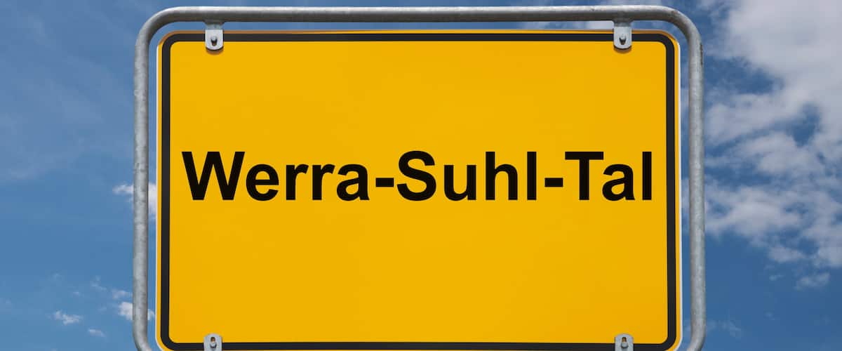 A yellow sign with the text "Werra-Suhl-Tal" against a blue sky with clouds.