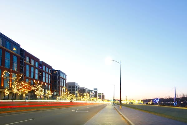 A city street at dusk with illuminated buildings and street lights.