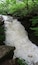 Une cascade d’eau qui dévale des rochers dans une zone boisée.