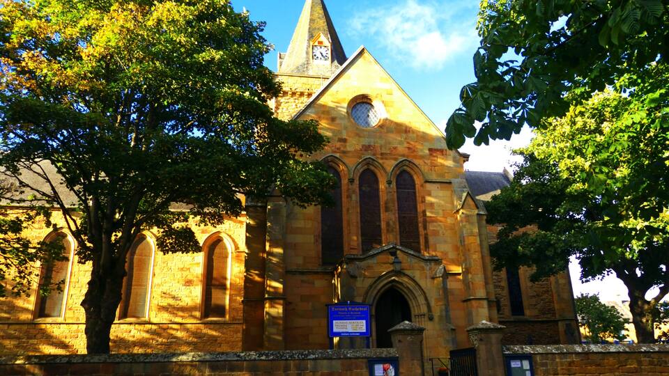 A historic church with a tall steeple, arched windows, and a clock.