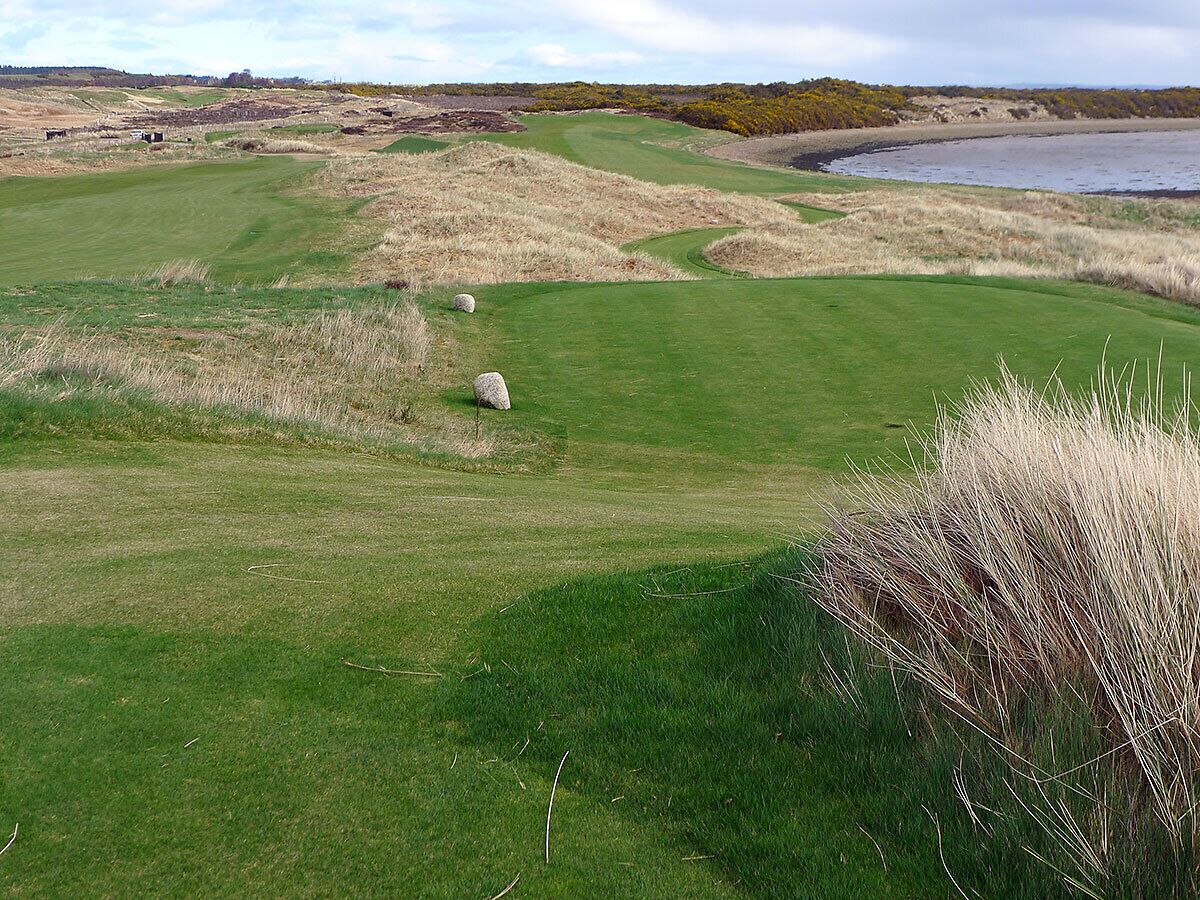 A golf course with a water body in the background.