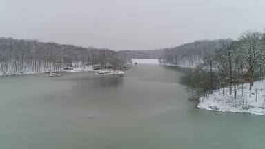A frozen river surrounded by snow-covered trees.