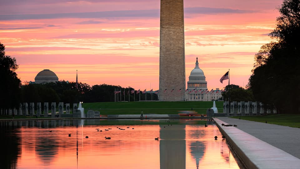 The Washington Monument, the U.S. Capitol building, and a reflecting pool at sunset.