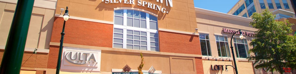 Ein Gebäude im Stadtzentrum von Silver Spring mit einer Uhr, Geschäften und einem Parkschild.