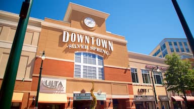 Um edifício no centro de Silver Spring com um relógio, lojas e um sinal de estacionamento.