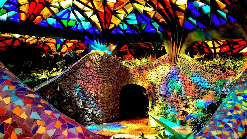 A colorful mosaic structure with a geometric roof and a central archway.