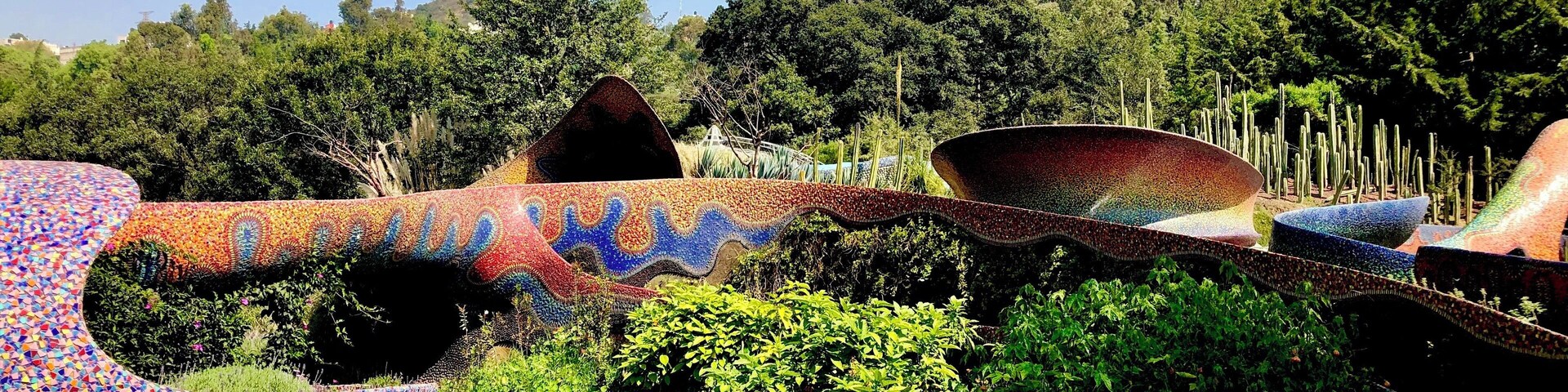 Un jardín con estructuras de mosaicos y abundante vegetación.
