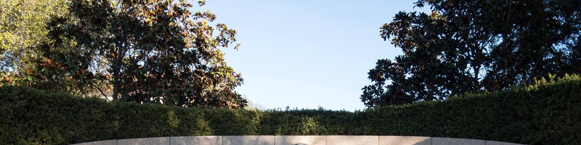 A memorial wall with inscriptions and a seal, surrounded by trees.
