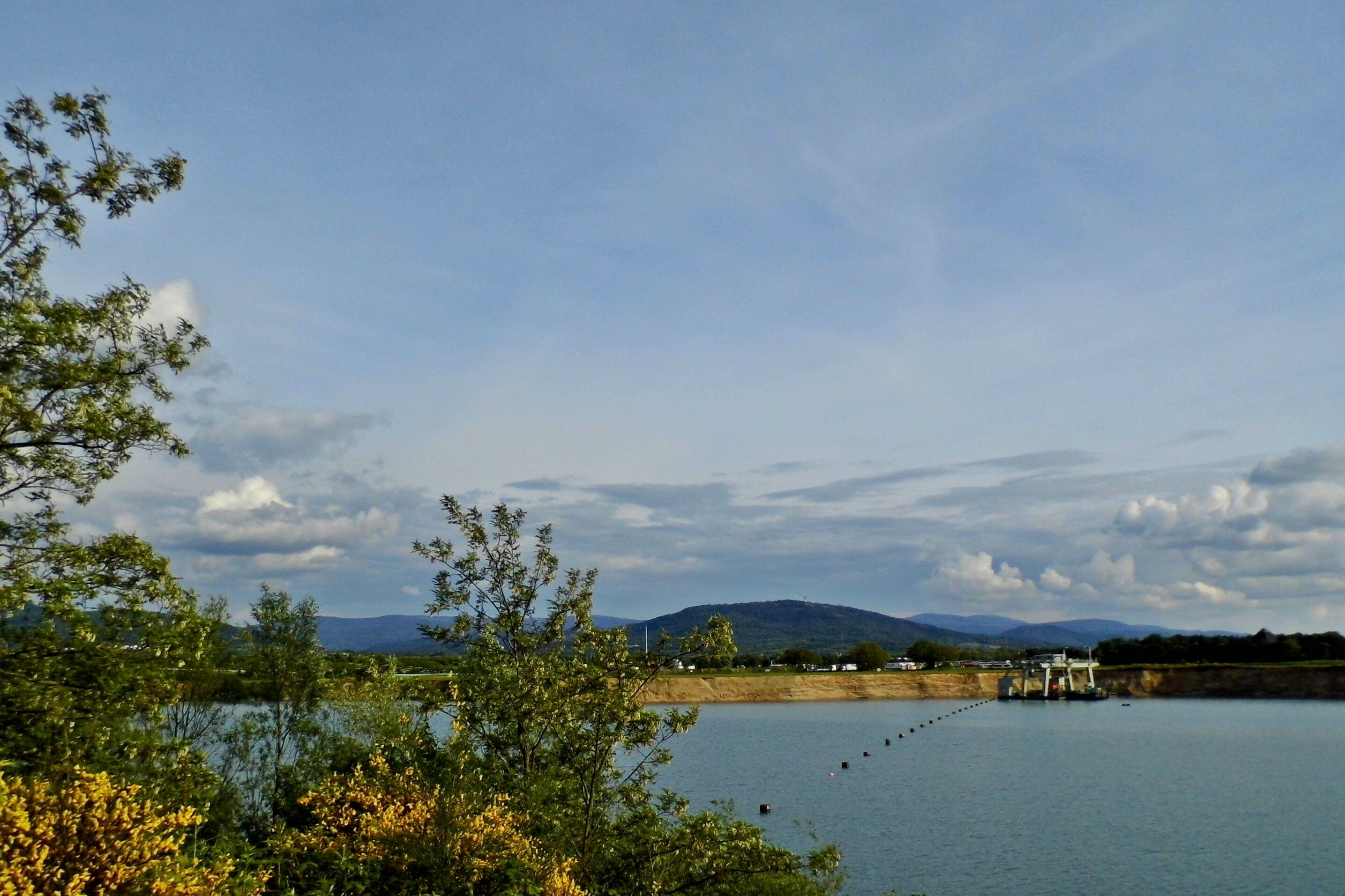 Un lago tranquilo con una presa y una montaña al fondo.