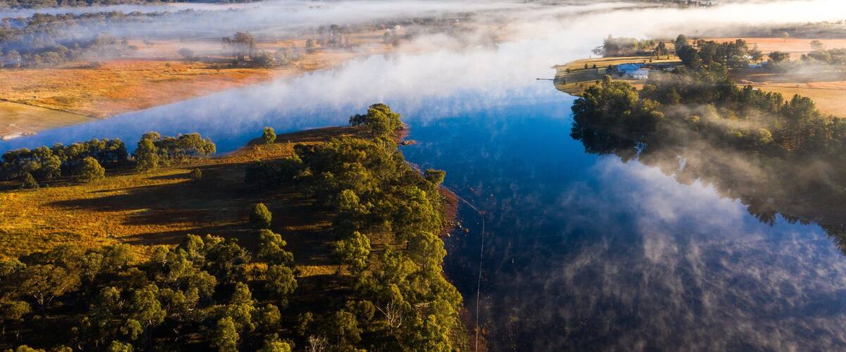 A lake surrounded by forested hills and a misty landscape.