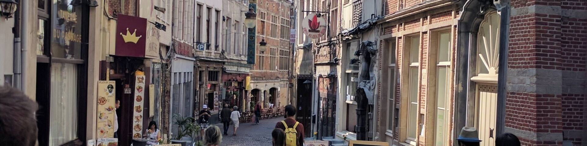 A cobblestone street lined with historic buildings, a street lamp, and a signboard.