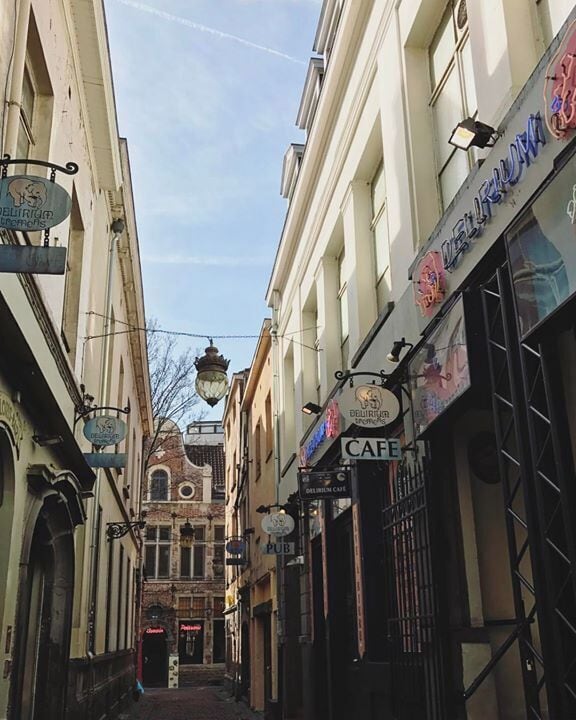 Une rue étroite, bordée de bâtiments des deux côtés, dont un café et un pub.