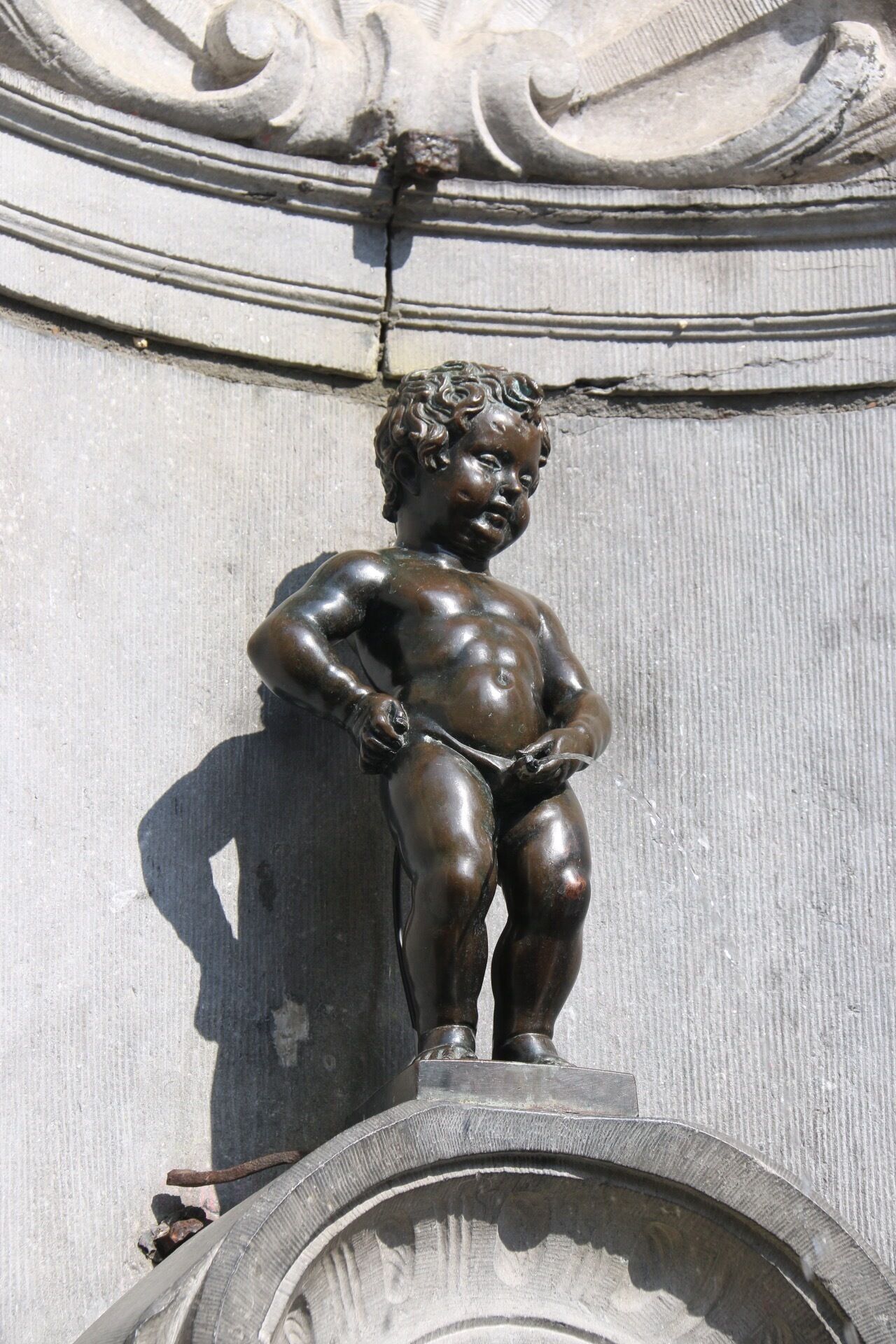 Manneken Pis is famous Brussels landmark put in place in 1618 or 1619 by Jerome Duquesnoy. It is known as Little Man Pee in Marols, a Dutch dialect spoken in Brussels. It is a small bronze fountain sculpture depicting a naked little boy urinating into the fountain's basin.