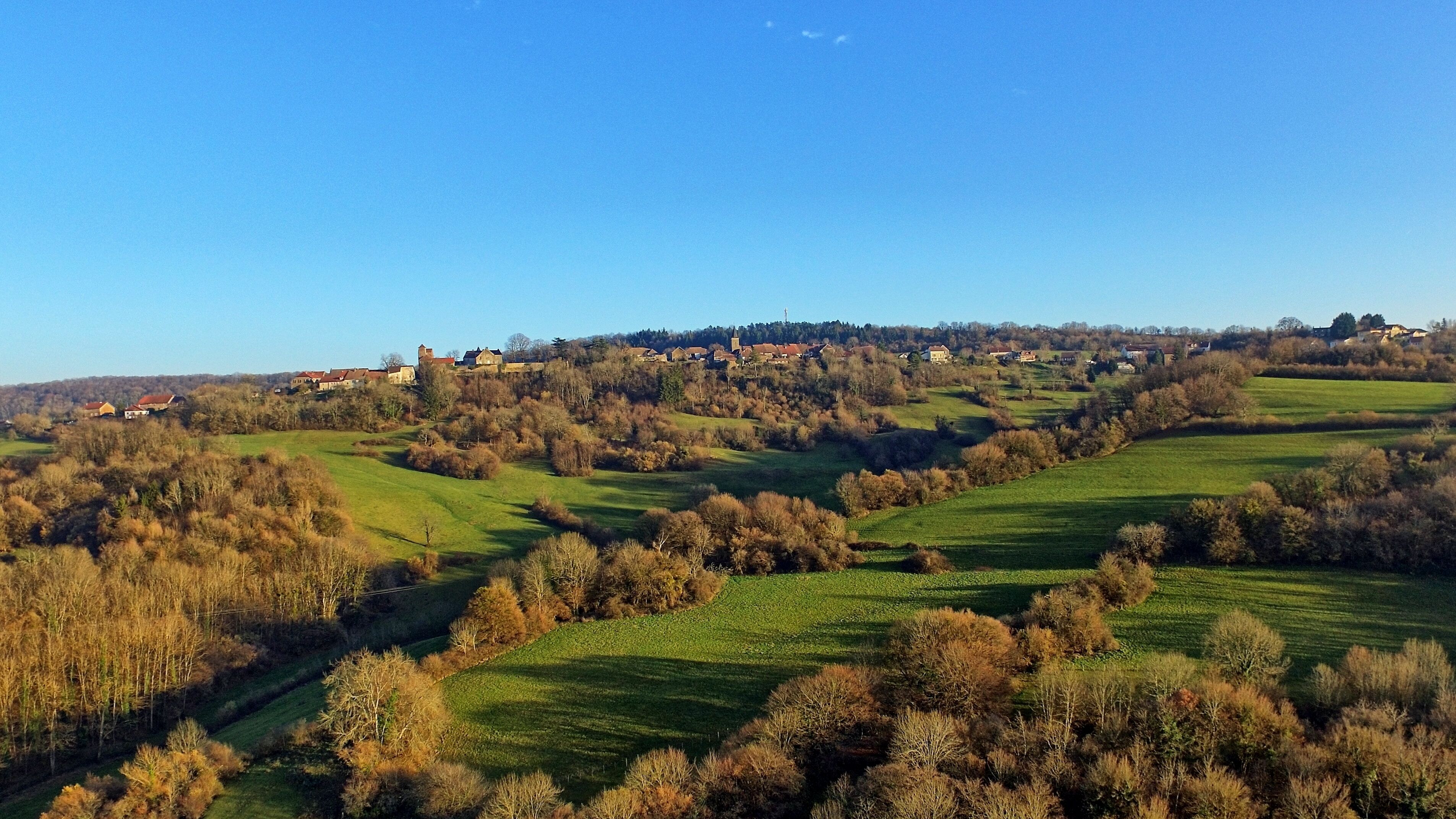 A rural landscape with rolling hills, scattered houses, and a prominent church on a hill.